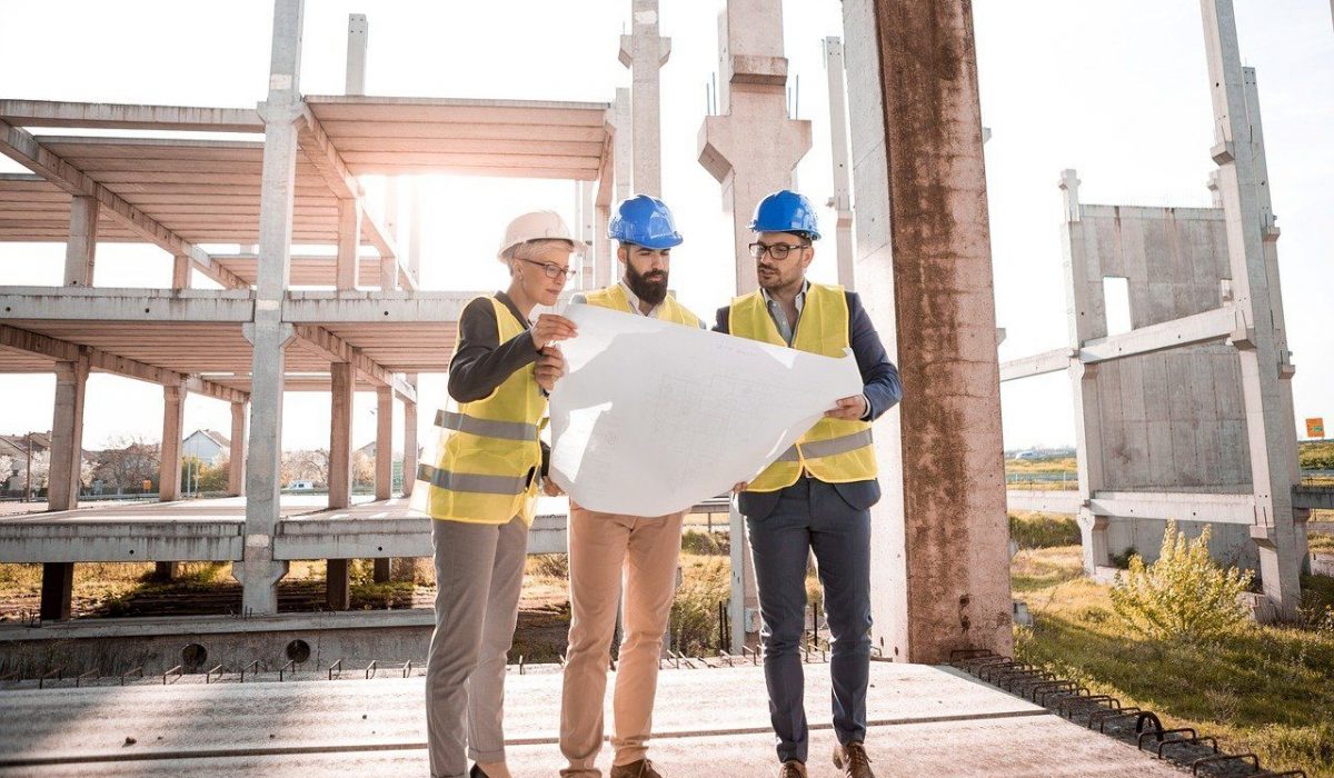Tres trabajadores de la construcción miran los planos de un proyecto.